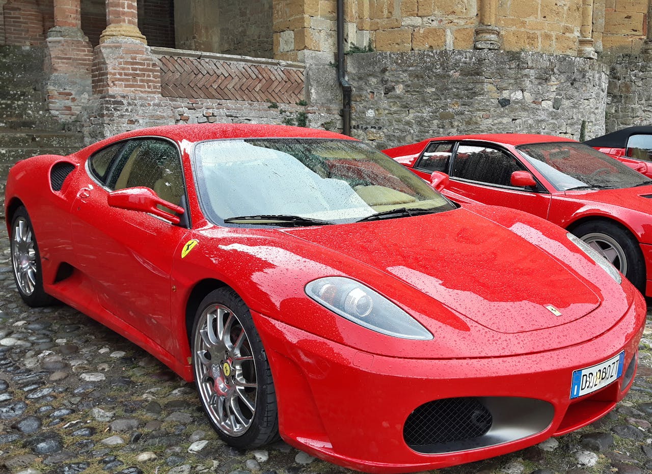 A vibrant red sports car parked outdoors on a historic cobblestone street, showcasing elegance.